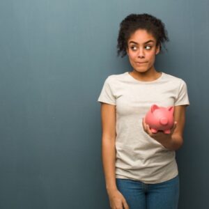 A woman nonchalantly holds a piggy bank